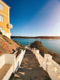 Footpath by sea against clear blue sky