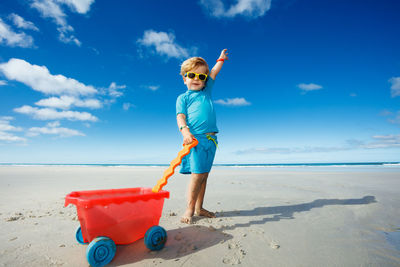 Rear view of boy standing at beach against sky