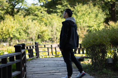 Rear view of woman walking on footpath amidst trees