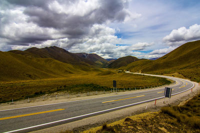 Scenic view of road by mountain against sky