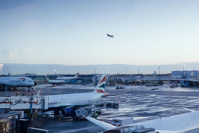 Airplanes on wet airport runway against sky at dusk