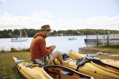 Man sitting on kayak on coast and looking away