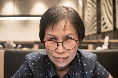 Close-up portrait of woman in eyeglasses sitting at restaurant