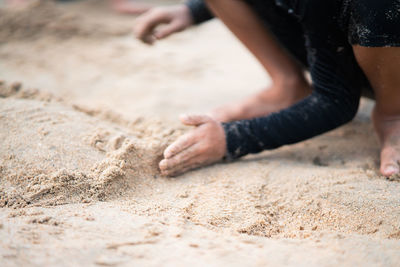 Low section of person relaxing on sand at beach