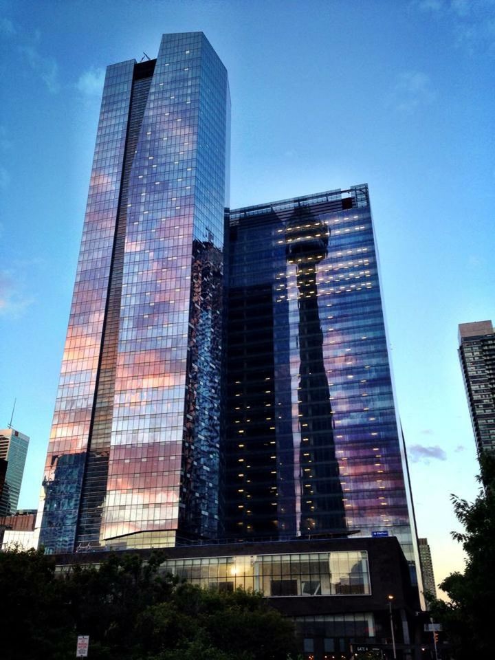 building exterior, architecture, skyscraper, built structure, modern, low angle view, city, office building, tall - high, tower, glass - material, building, sky, financial district, reflection, tall, city life, growth, sunlight, day