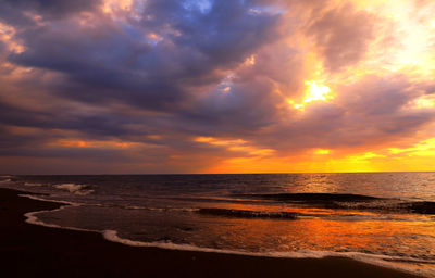 Scenic view of sea against cloudy sky during sunset