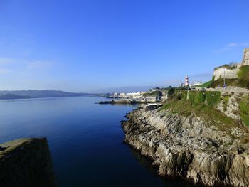 Panoramic view of town by sea against clear blue sky