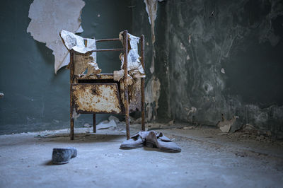 Abandoned shoes on floor against wall