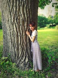 Full length of woman with tree trunk against plants