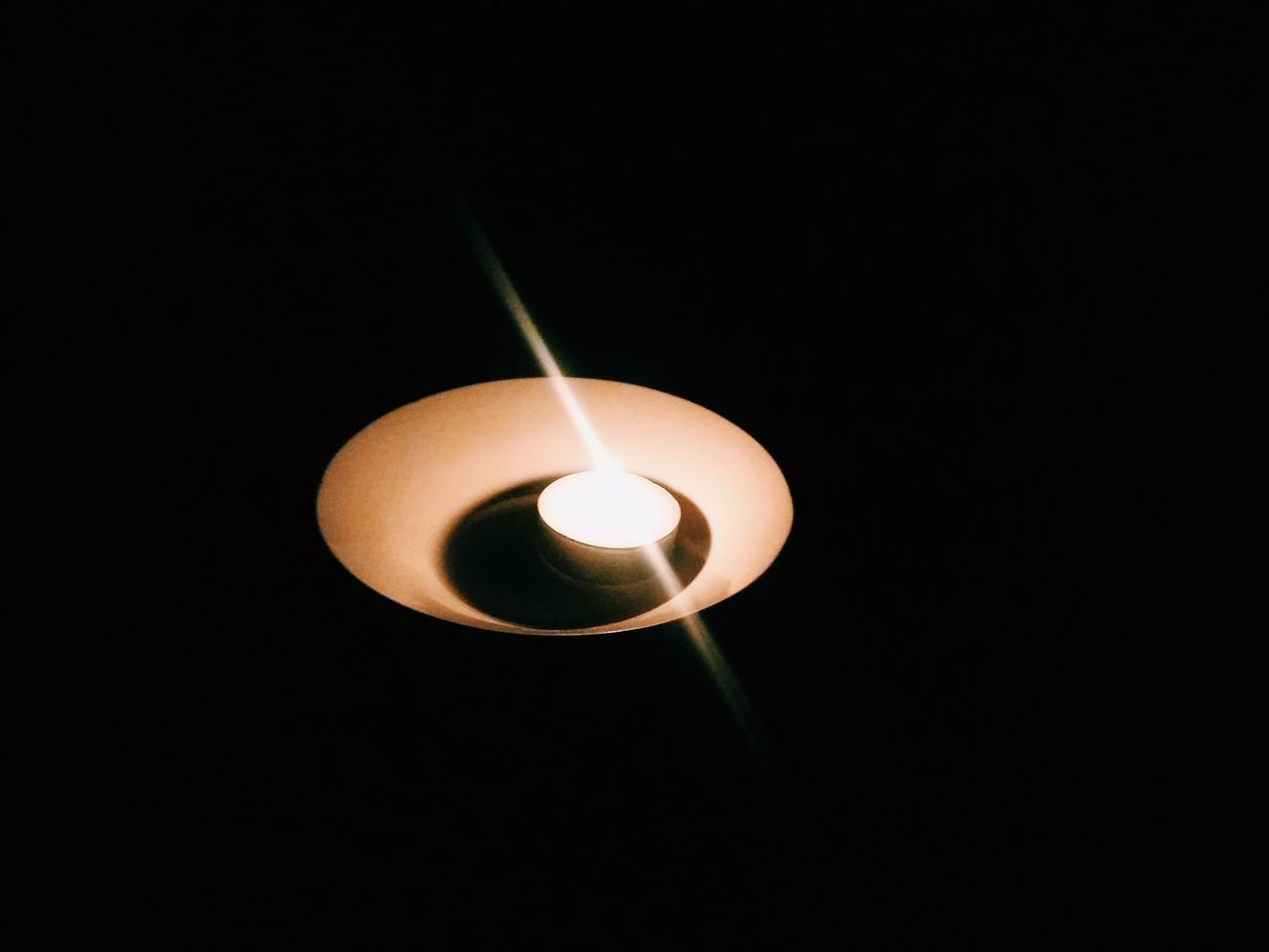 CLOSE-UP OF LIT CANDLE IN DARK