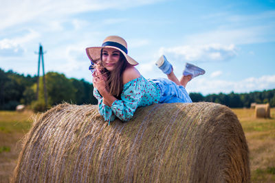 A beautiful young ukrainian woman lies on a hay bale and smiles