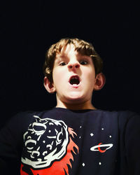 Portrait of boy against black background