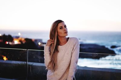 Portrait of young woman looking away against sky