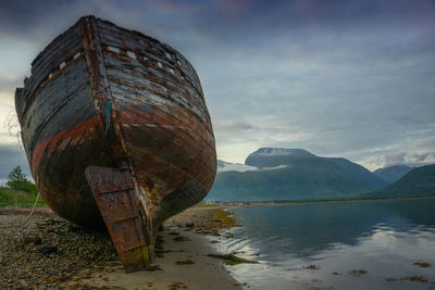 Abandoned boat on beach against sky