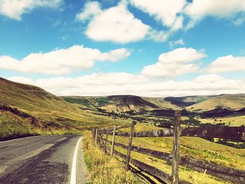 Scenic view of road amidst field against sky