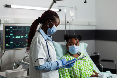 Female doctor wearing mask examining patient