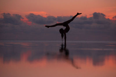 Full length of woman doing ballet dancing in infinity pool by sea against sky