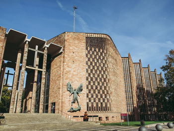 Statue of angel and building against sky