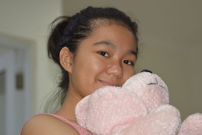 Portrait of a young girl holding a fluffy stuffed animal and smiling to the camera 