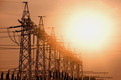 Low angle view of silhouette electricity pylon against sky during sunset