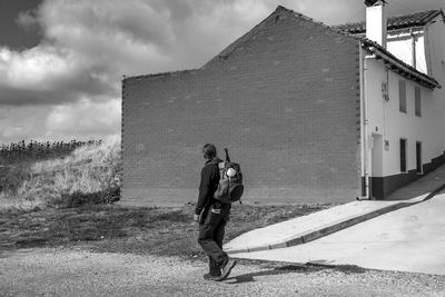 Full length rear view of man walking on road against sky