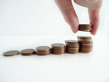 Cropped image of hand holding coin stack against white background