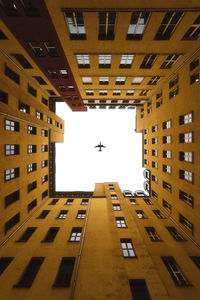 Directly below shot of airplane flying in sky over buildings