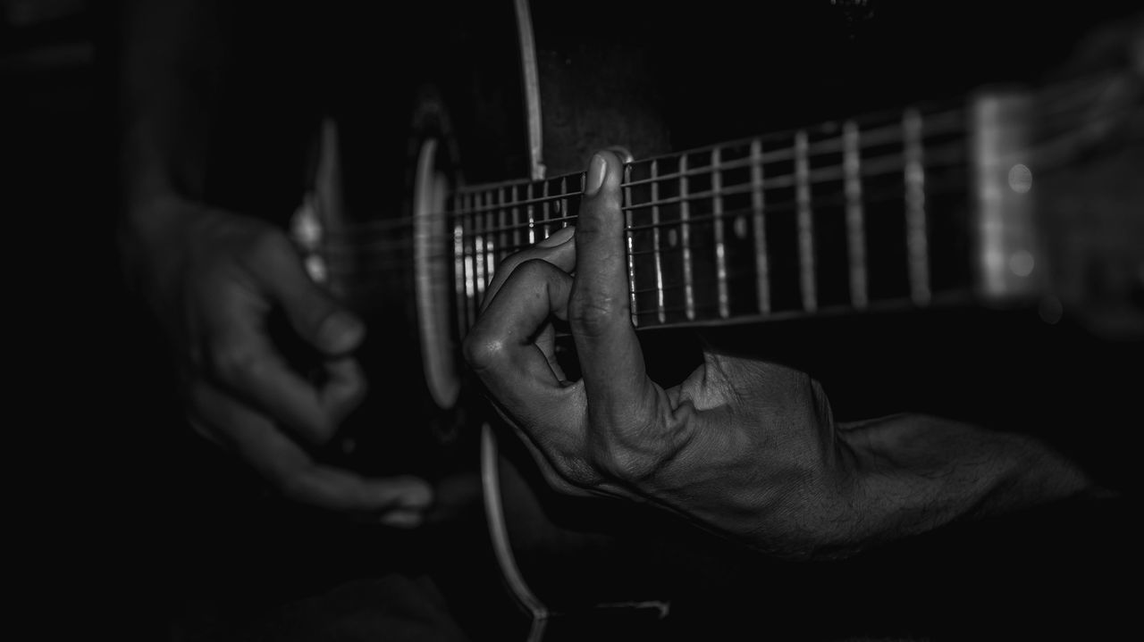 MIDSECTION OF MAN PLAYING GUITAR AT NIGHTCLUB