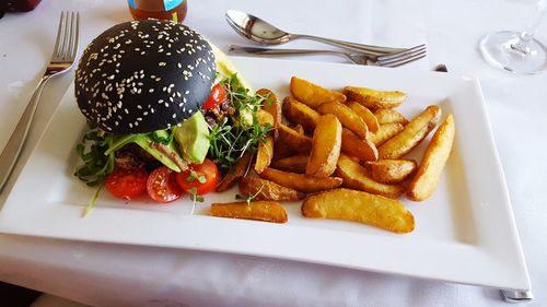 High angle view of burger with french fries served in plate on table