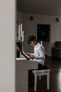 Side view of young man using laptop while sitting at home