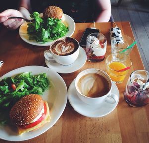 Woman eating salad with hamburger and coffee in restaurant