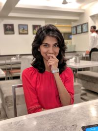 Portrait of beautiful young woman sitting on table