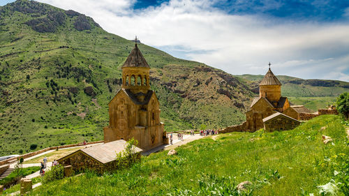 Built structure on field by buildings against sky