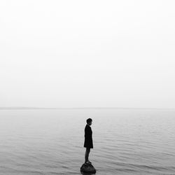 Man standing in sea against clear sky