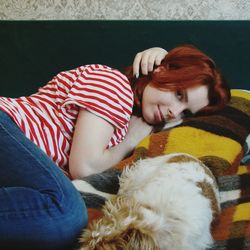 Portrait of woman with dog lying at home