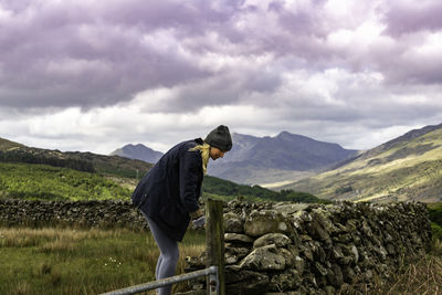 Side view of man standing on field against mountain range