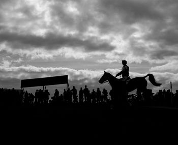 Silhouette people on stage against sky during sunset