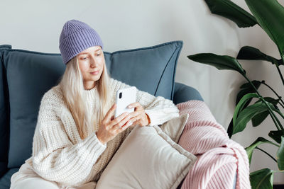 Portrait of young woman sitting on bed at home