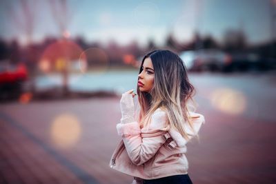 Portrait of a smiling young woman standing against sky during sunset