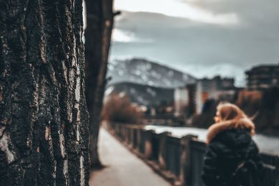 Rear view of woman on tree trunk against sky