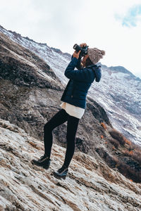 Full length of woman photographing on rock