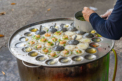 Woman making banh khot- vietnamese tiny shrimp pancake on skillet