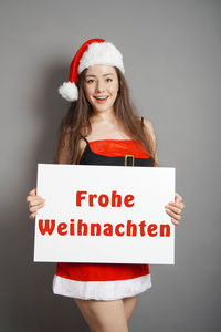 Portrait of smiling young woman standing against black background