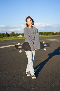 Portrait of young woman standing on road