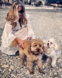 Smiling woman playing with dogs at beach