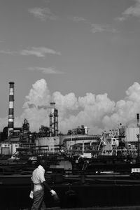 Man walking against power station against sky