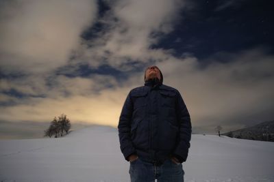 Man standing on snow on field against sky during winter