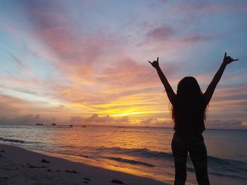 Silhouette person standing on beach against sky during sunset