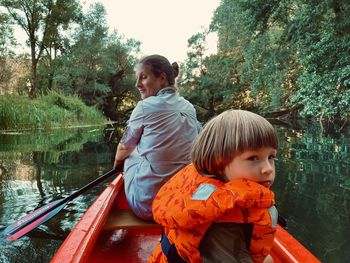 Boy looking at boat against trees