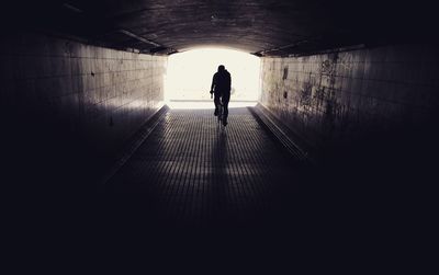 Rear view of silhouette man walking in tunnel